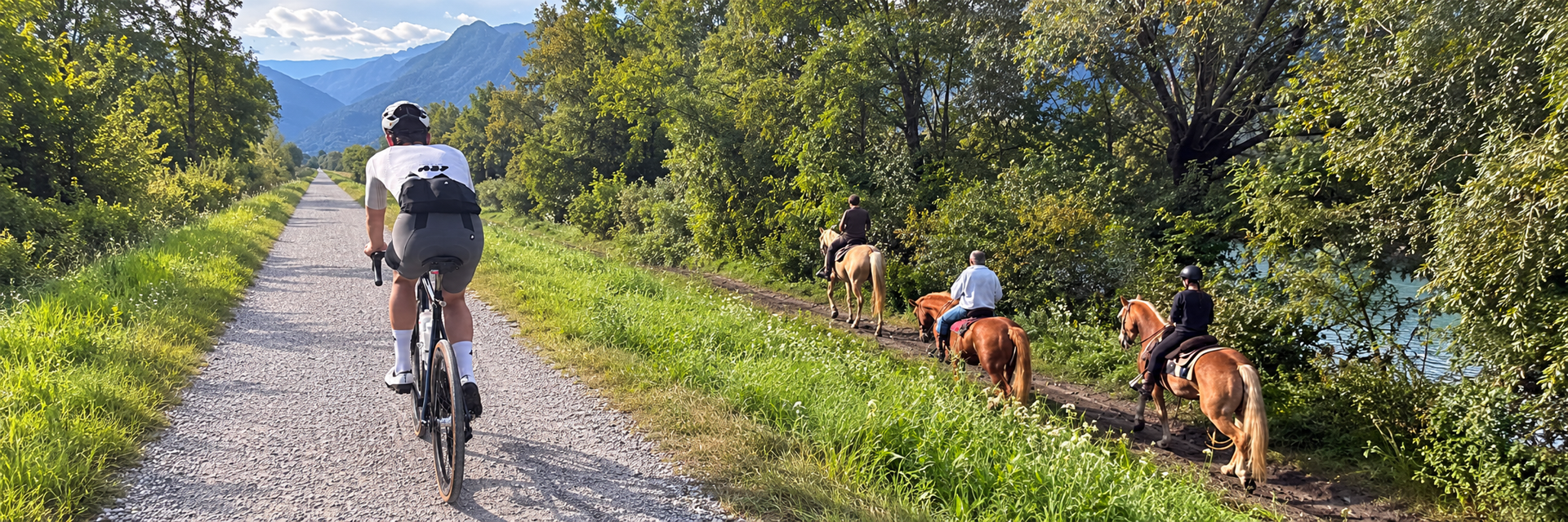 A gravel cyclist and horse riders exploring quiet trails beneath the mountains