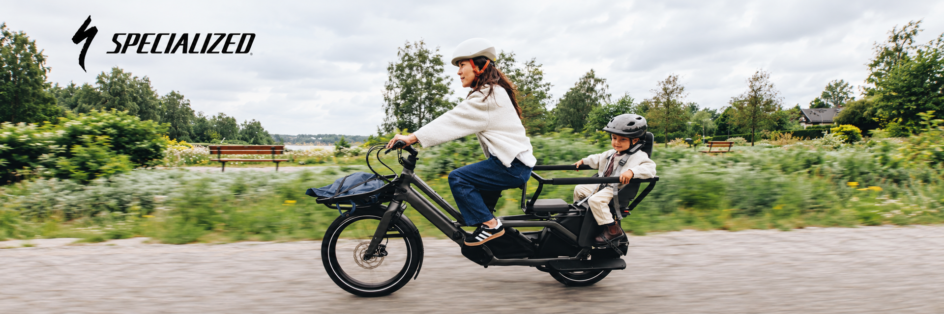 A mother and child enjoying a park ride on a Specialized electric cargo bike