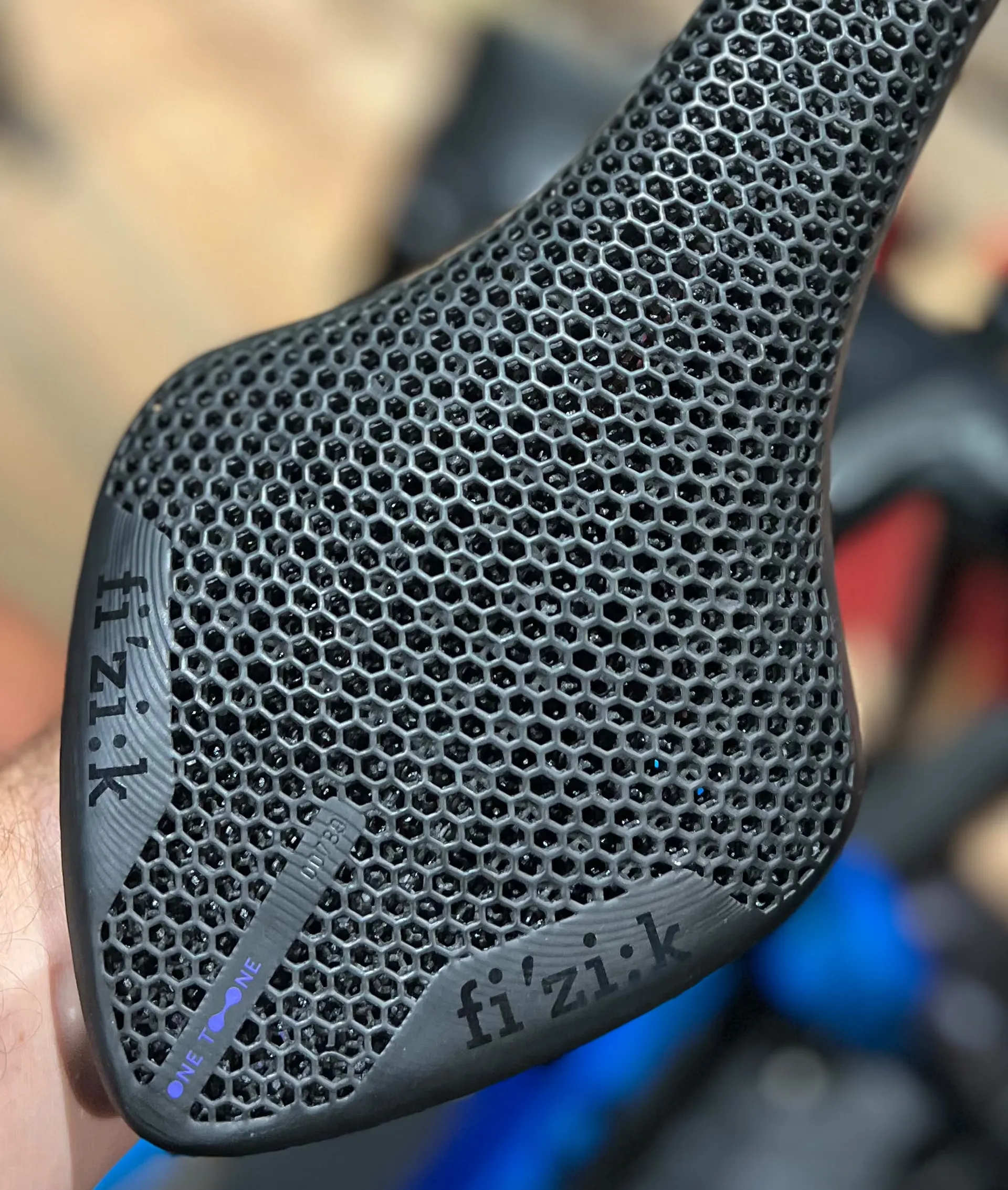 Close-up of the 3D-printed lattice cushioning and One-to-One branding on a Fizik saddle