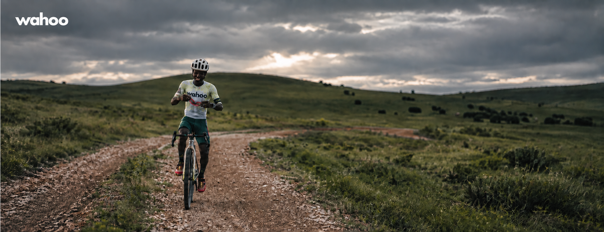 Cyclist wearing a Wahoo jersey on a gravel track through rolling countryside